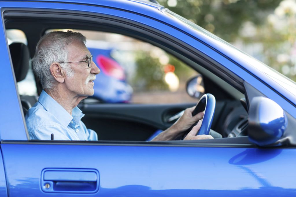 Retired elder man driving a blue car